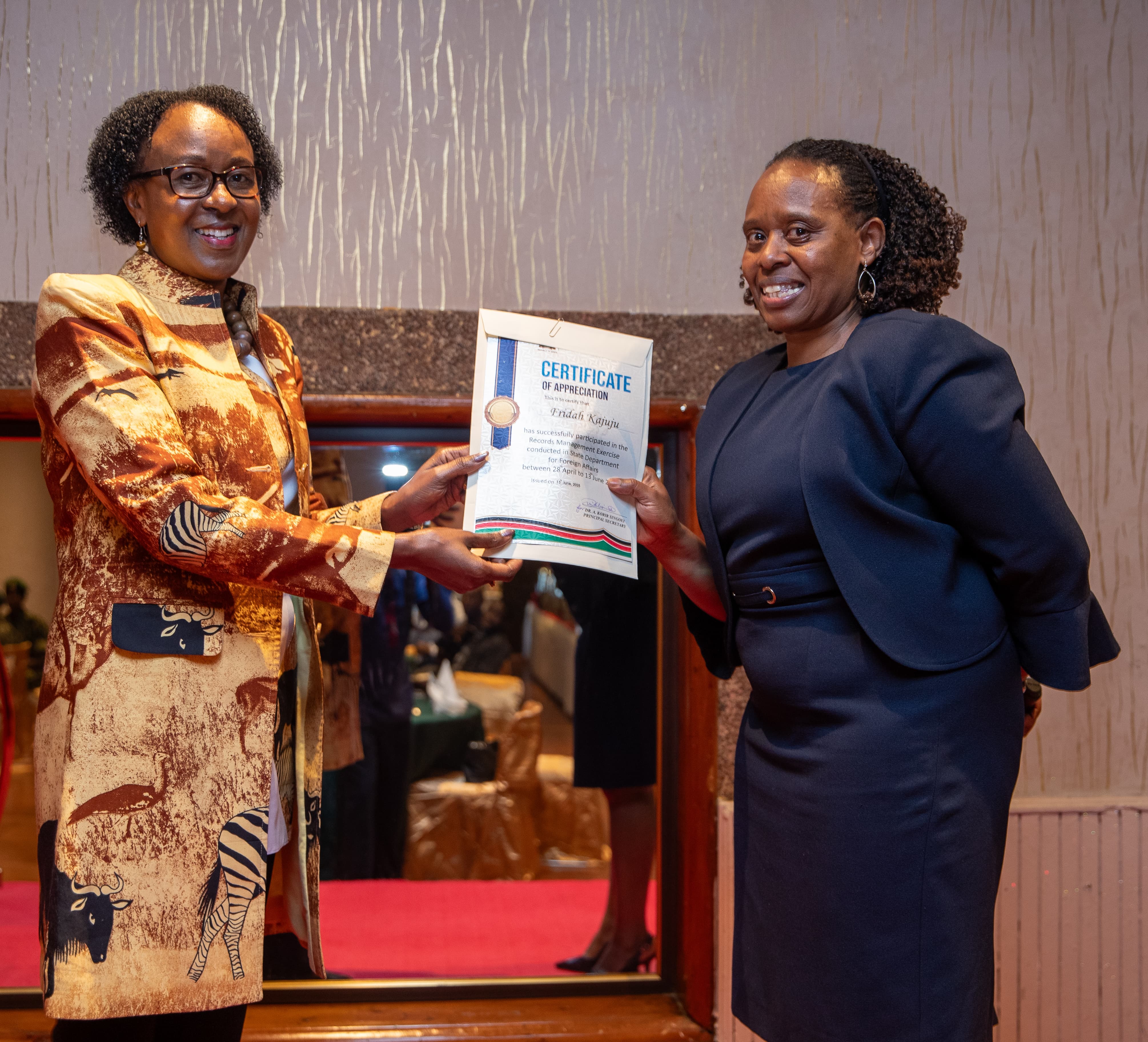 Ag. Director General, Political and Diplomatic Affairs, Amb. Lucy Kiruthu hands certificate to Director Frida Kajuju